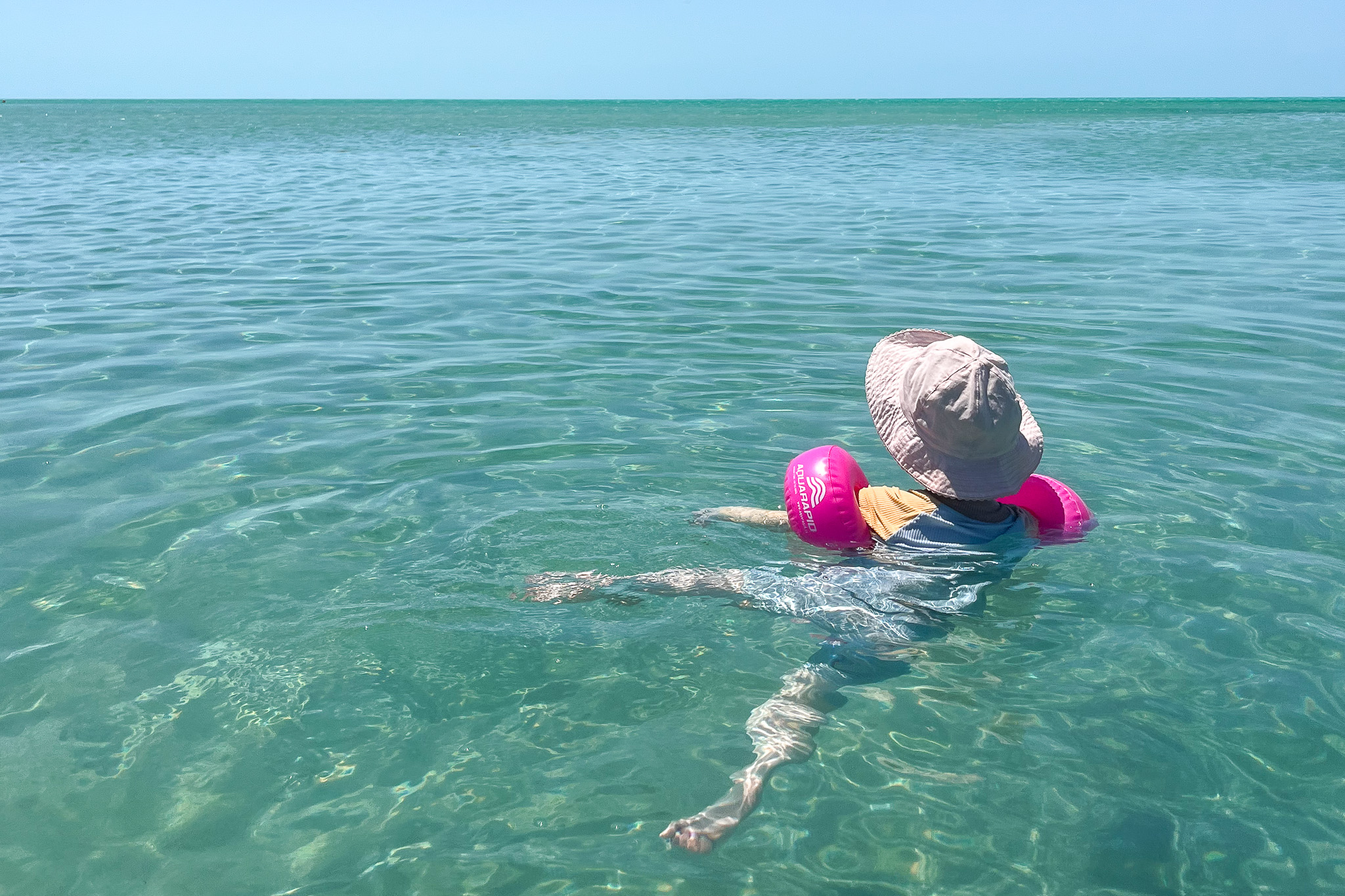 De peuter zwemt in de turquoise zee van Ambergris Caye, San Pedro