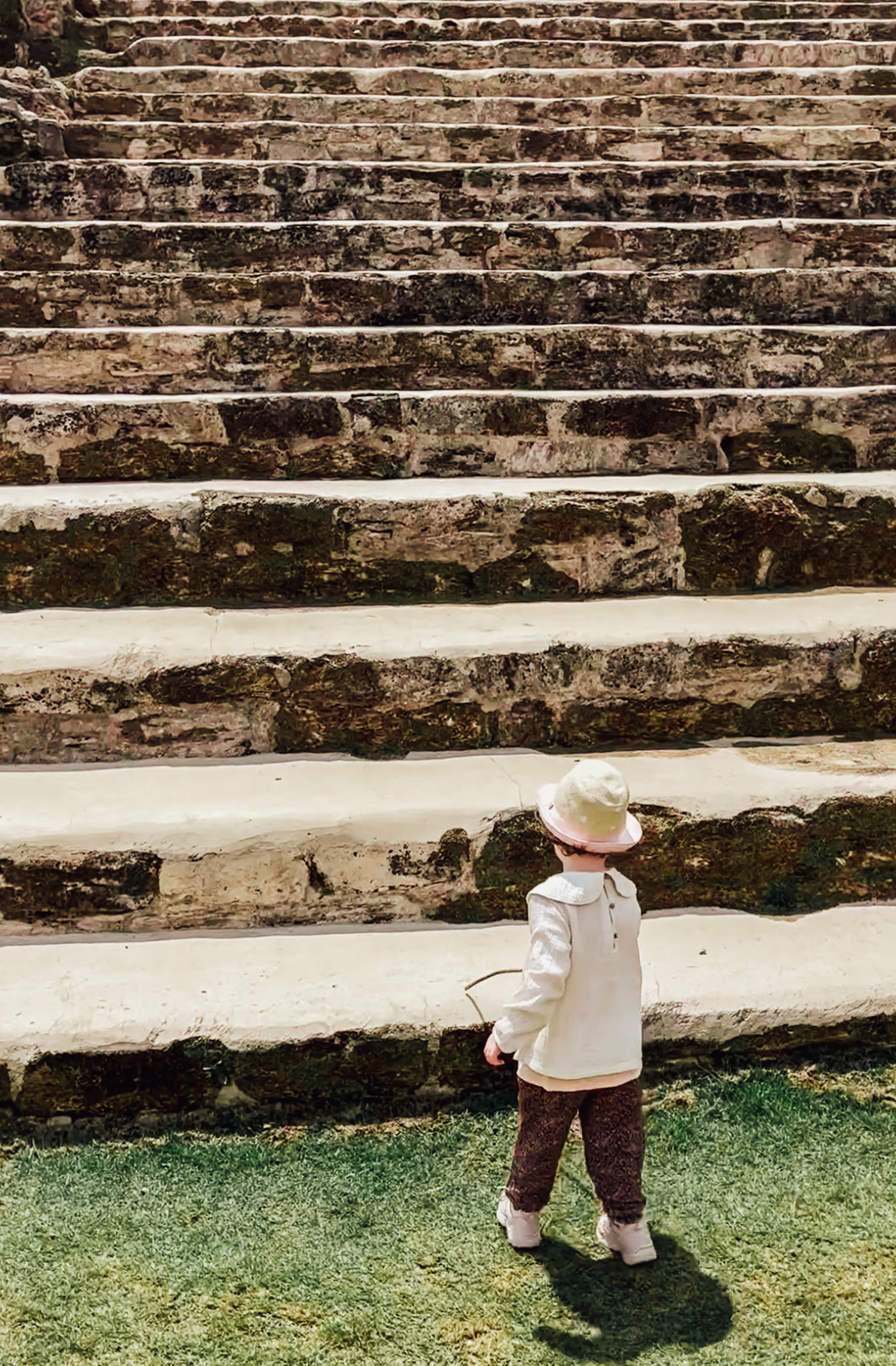 Peuter met een stok die de wegweest bij de trappen van Maya ruïne Altun Ha.